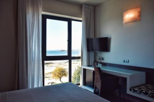 ビラガルシーア・デ・アロウサにあるHotel Alda Carrilのベッド付きのホテルルームで、海の景色を望めます。