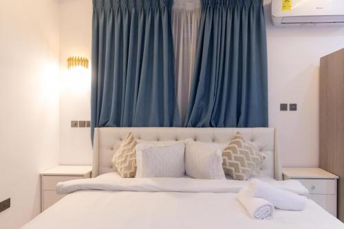 Un dormitorio con una gran cama blanca con cortinas azules. en Premier Studio Apartment, East Airport, en Accra