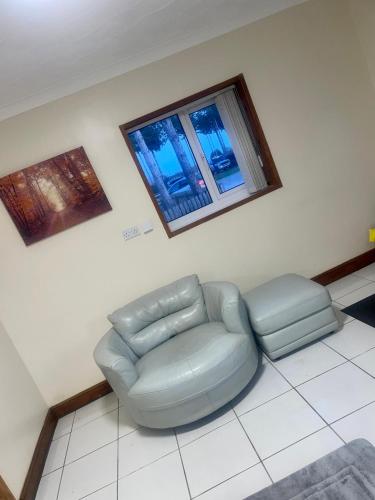 a living room with a couch and a chair and two windows at Beautiful 3-Bed Bungalow in Bawtry Doncaster in Doncaster