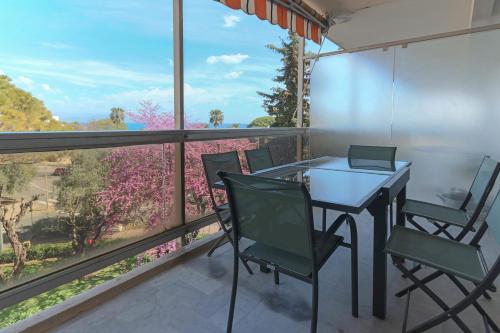 un balcon avec une table, des chaises et une fenêtre dans l'établissement Beautiful flat with Sea View Terrace Pool Parking portative AC- BENAKEY, à Antibes