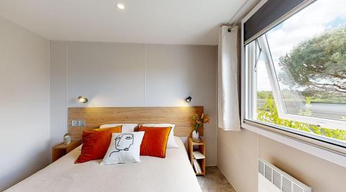 Ambérieux-en-DombesにあるL'Oasis des Dombesのベッドルーム1室(オレンジ色の枕と窓付)