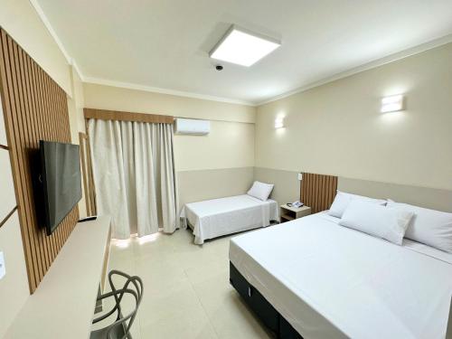 a hotel room with two beds and a flat screen tv at Spazzio Diroma - com acesso Acqua Park in Caldas Novas