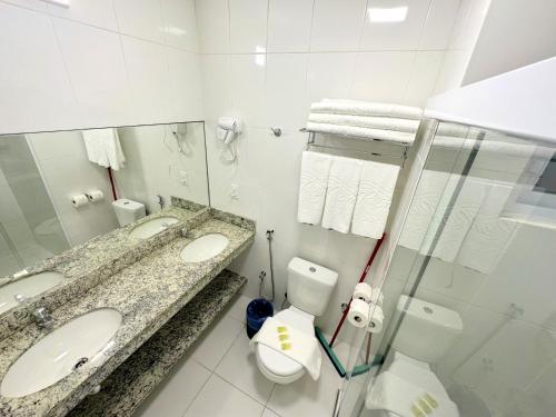 a bathroom with two sinks and a toilet and a mirror at Spazzio Diroma - com acesso Acqua Park in Caldas Novas