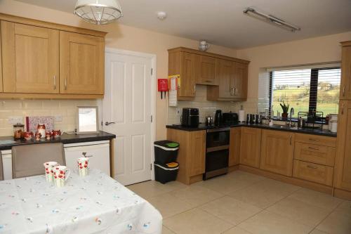 a kitchen with wooden cabinets and a table in it at 3 Bed Farmhouse - Sleeps 6 - Wifi - Parking in Omagh