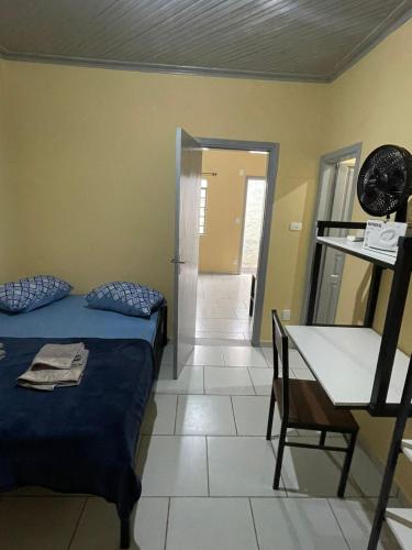 a bedroom with a bed and a table and a desk at Apto 1 ótimo local próximo shopping in Campo Grande