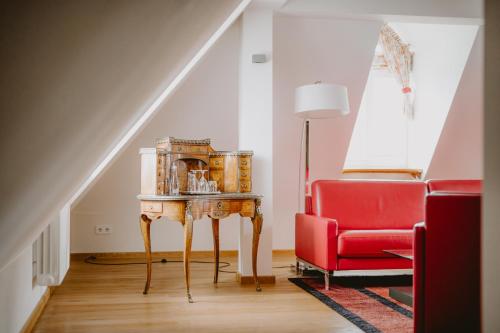 a living room with a red chair and a table at Pałac Pakoszów Schlosshotel Wernersdorf in Jelenia Góra