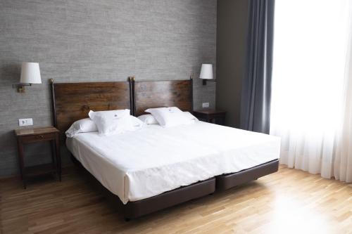 a bedroom with a large bed with white sheets and pillows at Balneario de Mondariz in Mondariz-Balneario