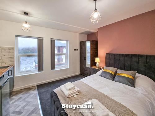 a bedroom with a large bed and two windows at Stylish 10 Bedrm House, Fast Wifi, Free Parking in Manchester
