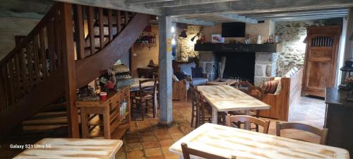 a restaurant with wooden tables and chairs and a staircase at Le Refuge in Genouillac