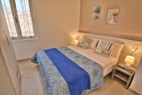a small bedroom with a bed with a blue blanket at Appartamento Orizzonte - Rebomaholidays in Tignale