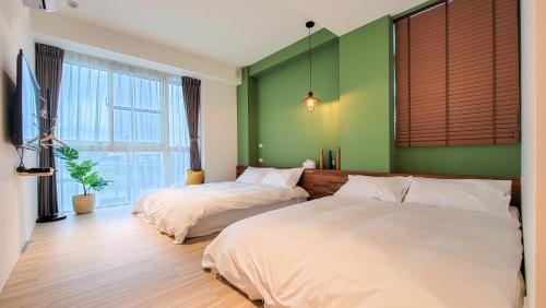 2 Betten in einem Zimmer mit grünen Wänden in der Unterkunft Mo Guesthouse in Shangwu