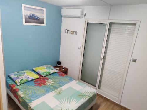 - une petite chambre avec un lit et un mur bleu dans l'établissement F2 PARC TRINITE, à Saint-Denis