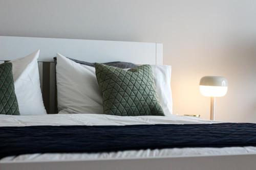 Una cama con almohadas verdes y blancas y una lámpara. en Luxury Ensuite Room - With Full Privacy as only room on the top floor!, en Dublín