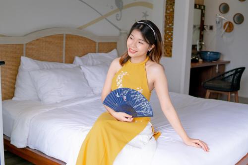 a woman in a yellow dress sitting on a bed at Seahorse Signature Danang Hotel by Haviland in Da Nang