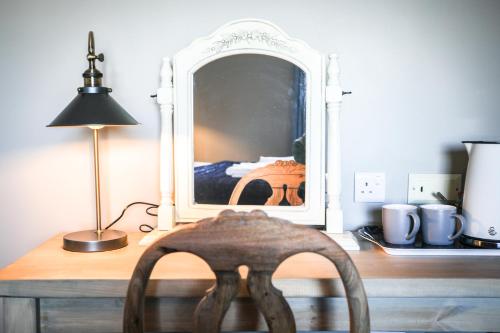 a wooden desk with a chair in front of a mirror at The Lazy Goose - Coffee House & Bedrooms in Stonehouse