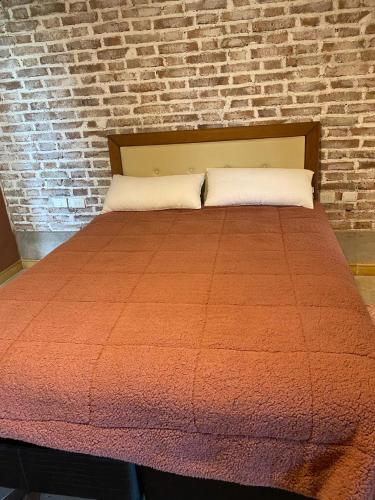 1 cama con edredón naranja y pared de ladrillo en San Polo departamentos en La Consulta