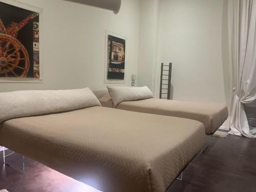 two beds in a room with white walls at Cinquecento B&B in Barcellona-Pozzo di Gotto