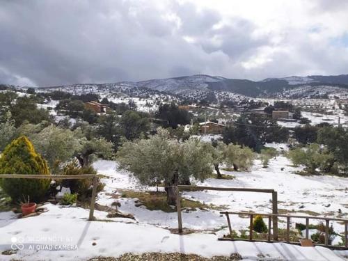 una colina cubierta de nieve con una ciudad a lo lejos en Casa La Colina Mandarina II Casa de madera, en Tahal