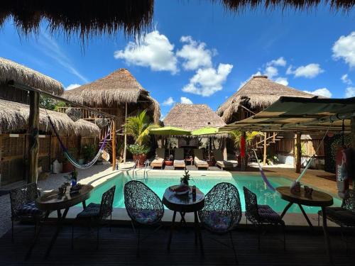 a pool at a resort with chairs and a swing at Jungla y Estrellas in Cobá
