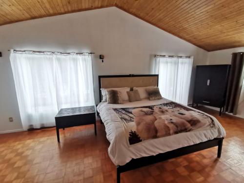 um quarto com uma cama grande e 2 janelas em Domaine de la rivière Montmorency, chalet luxueux em Sainte Brigitte de Laval