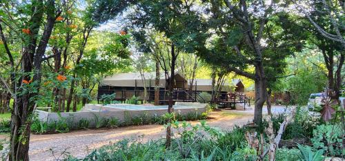 a garden with a building in the midst of trees at Tot Hier Toe in Phalaborwa