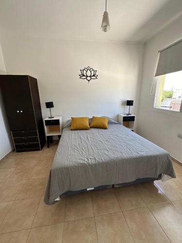 a bedroom with a bed with two yellow pillows on it at Departamentos Crisol in San Fernando del Valle de Catamarca