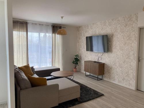 a living room with a couch and a tv on a wall at Villa by Nesma in Châtellerault