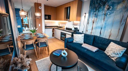 a living room with a blue couch and a kitchen at Apartamenty Cicha, Sun & Snow in Krynica Zdrój