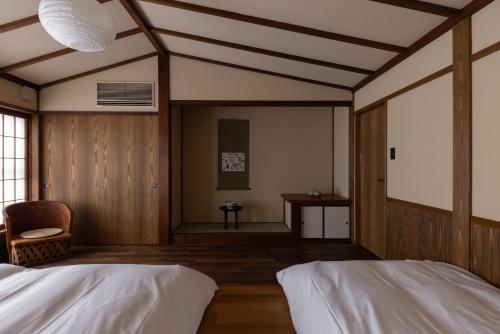 a bedroom with two beds and a chair and a table at 杜人舎 Morito-Sha in Nanto