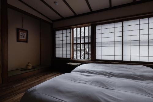 a bedroom with a white bed and windows at 杜人舎 Morito-Sha in Nanto