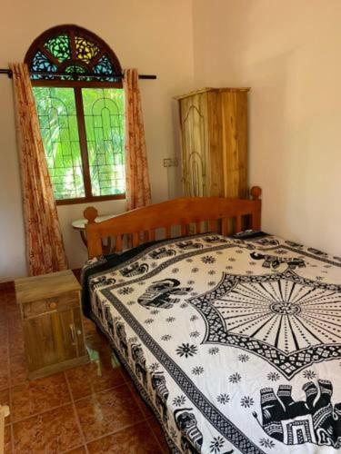 Habaraduwa Central的住宿－Shadow lake villa，一间卧室设有一张床和一个彩色玻璃窗
