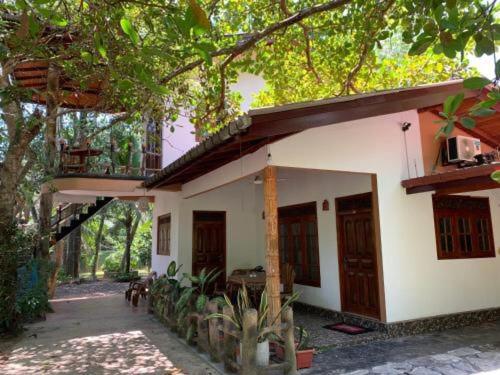 ein kleines weißes Haus mit Balkon darüber in der Unterkunft Shadow lake villa in Habaraduwa Central