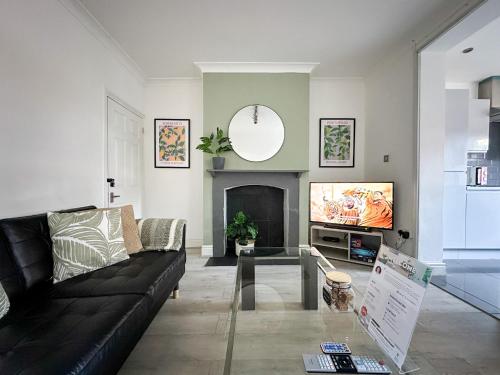 a living room with a black couch and a tv at Stylish & Spacious City Centre 3-Bedroom Townhouse - Sleeps 6 in Canterbury