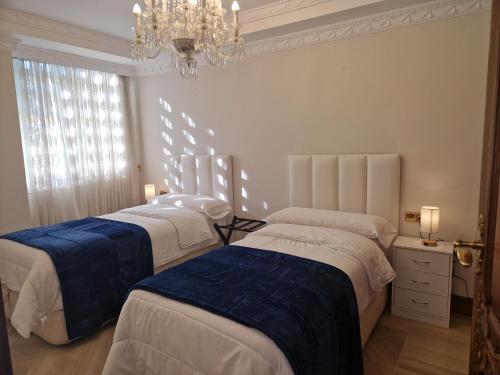 two beds in a room with a chandelier at Apartamento Centro Marbella in Marbella
