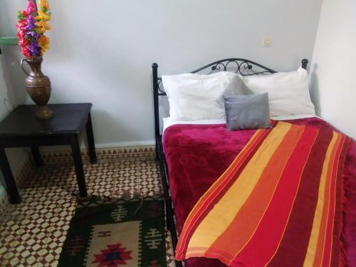a bed with a colorful blanket and a side table at HOTEL EL AMAL in Marrakech