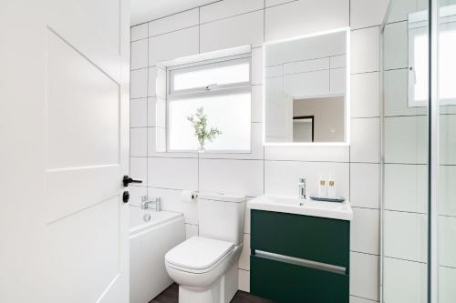 a white bathroom with a toilet and a sink at Yewbeck: brand new, garden views in Windermere