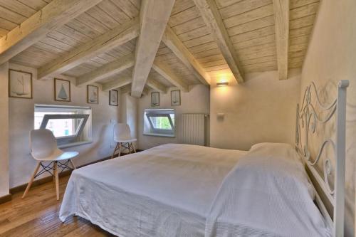 um quarto com uma grande cama branca e 2 cadeiras em Appartamento Al Porto Vecchio - Rebomaholidays em Gargnano