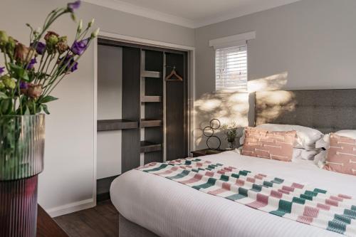 a bedroom with a large bed and a vase of flowers at Yewbeck: brand new, garden views in Windermere