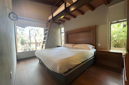 a bedroom with a bed with a ladder and two windows at Casa con alberca y jacuzzi in Avándaro
