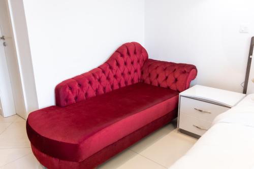 a red couch sitting in a room next to a bed at Modern Studio Apartment, Lennox in Accra