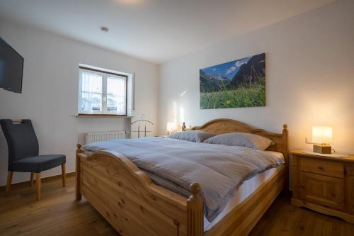 1 dormitorio con 1 cama grande de madera y 1 silla en Ferienwohnungen Alpentraum - TraumZeit, en Oberstdorf
