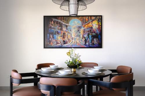 a dining room table with a painting on the wall at Fraser Suites Al Liwan in Manama