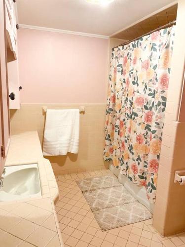 La salle de bains est pourvue d'une douche avec rideau de douche fleuri. dans l'établissement 5- Bed Pink house ( Close to Sports Center ), à West Monroe