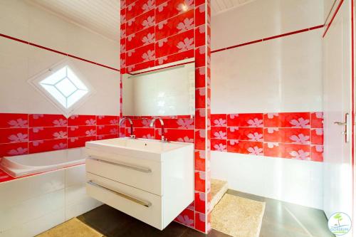 La salle de bains rouge et blanche est pourvue d'un lavabo et d'une baignoire. dans l'établissement Magnifique Villa pour 10 personnes à Parentis en Born, à Parentis-en-Born