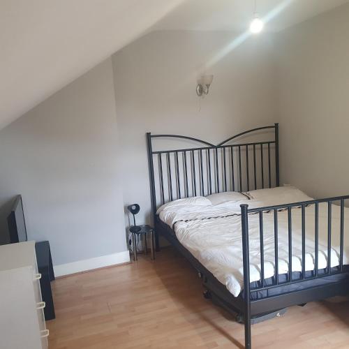 a bedroom with a bed in a white room at Flat with excellent transport links to central London. in Elmers End