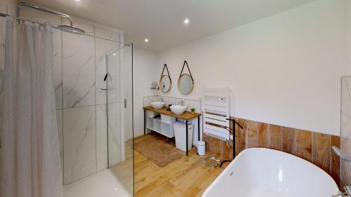 een badkamer met een bad, een douche en een wastafel bij Maison TYMAO de 14 personnes en bord de Mer in Étables