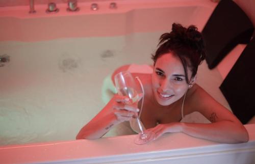 a woman in a bath tub holding a glass of wine at B&B GRECALE Suite & Spa in Rende