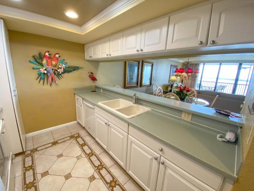 a kitchen with white cabinets and a sink and a mirror at Resort Harbour Properties - Fort Myers / Sanibel Gateway in Punta Rassa