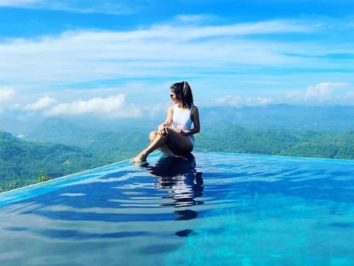 a woman sitting on top of a infinity pool at Green Acres Leisure Resort & Spa in Kandy