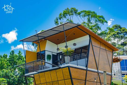 une maison avec un grand balcon en face des arbres dans l'établissement Glamping LaMoro, à Sevilla